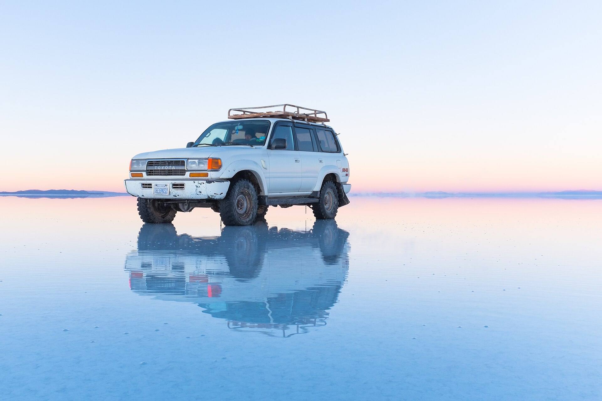 Un todoterreno blanco reflejado en el agua del salar; imagen del destino, sin identificar un operador.