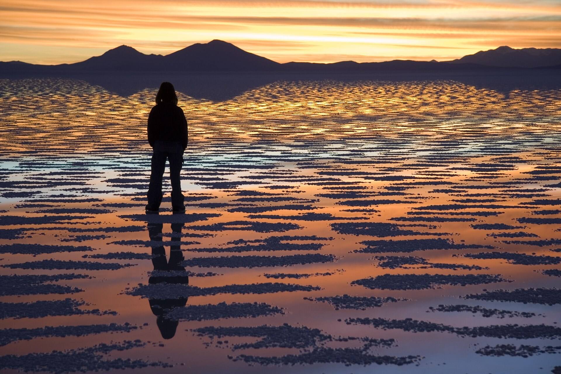 A person watches sunset over salt and water.